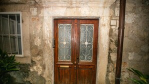 A wooden door with intricate metalwork, set in a weathered wall with a small window to the left. - Rooms Epidaurus (Dubrovnik)