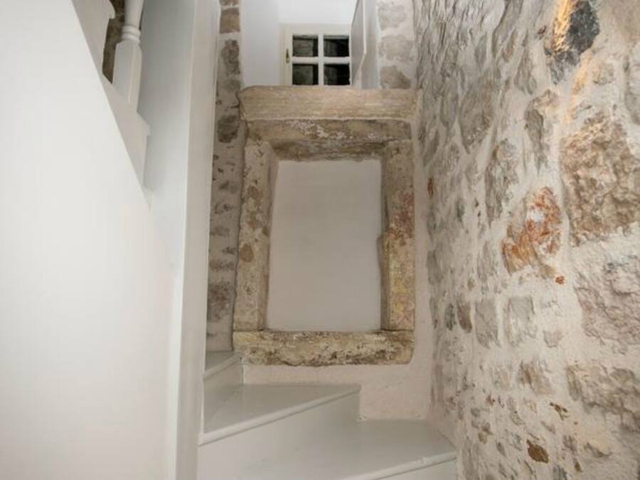 Una escalera estrecha con peldaños blancos que conduce a un muro de piedra.