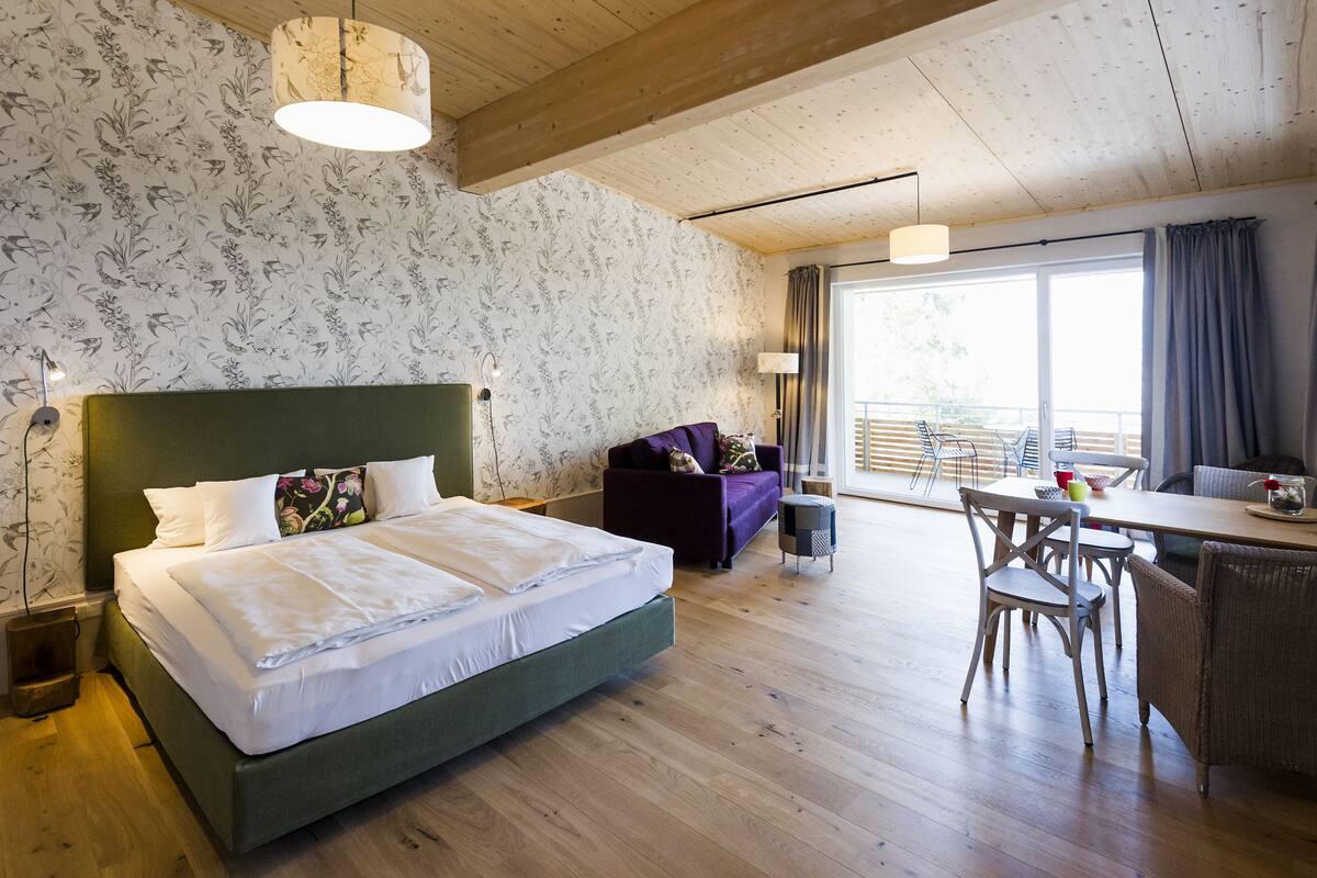 Una habitación con una cama, un sofá, una mesa de comedor y sillas.