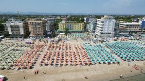 Vista aérea de una playa con numerosas sombrillas y gente.