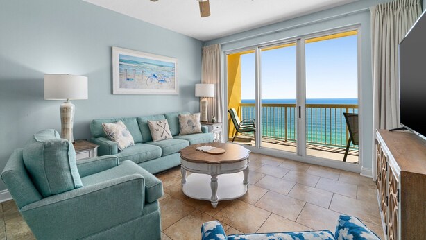 Un salon avec un canapé, une table basse et un téléviseur. Il y a un balcon avec vue sur l’océan.