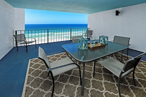 A balcony with a glass table, chairs, and a view of the ocean. - Watercrest 1005 (Panama City Beach)