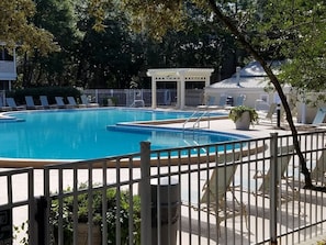 A swimming pool with a white fence, lounge chairs, and a covered area. - Villa 18 at Hidden Dunes (Miramar Beach)
