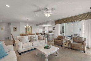 A spacious living room with a white sofa, beige armchairs, a coffee table, and a ceiling fan. - Villa 18 at Hidden Dunes (Miramar Beach)