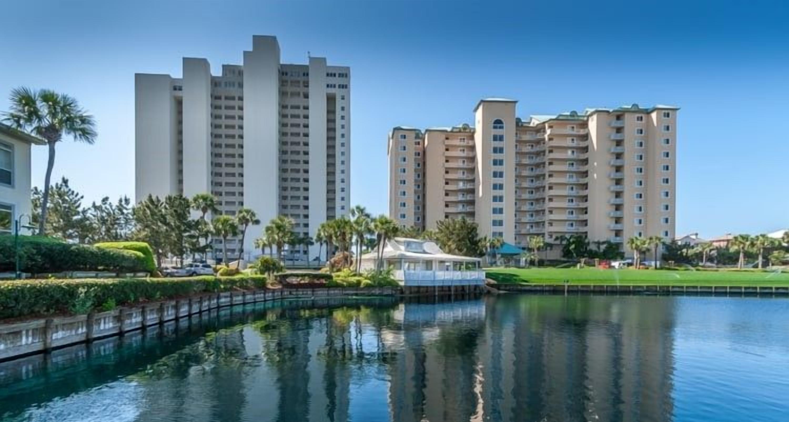 A waterfront hotel with multiple high-rise buildings, a dock, and well-maintained greenery.