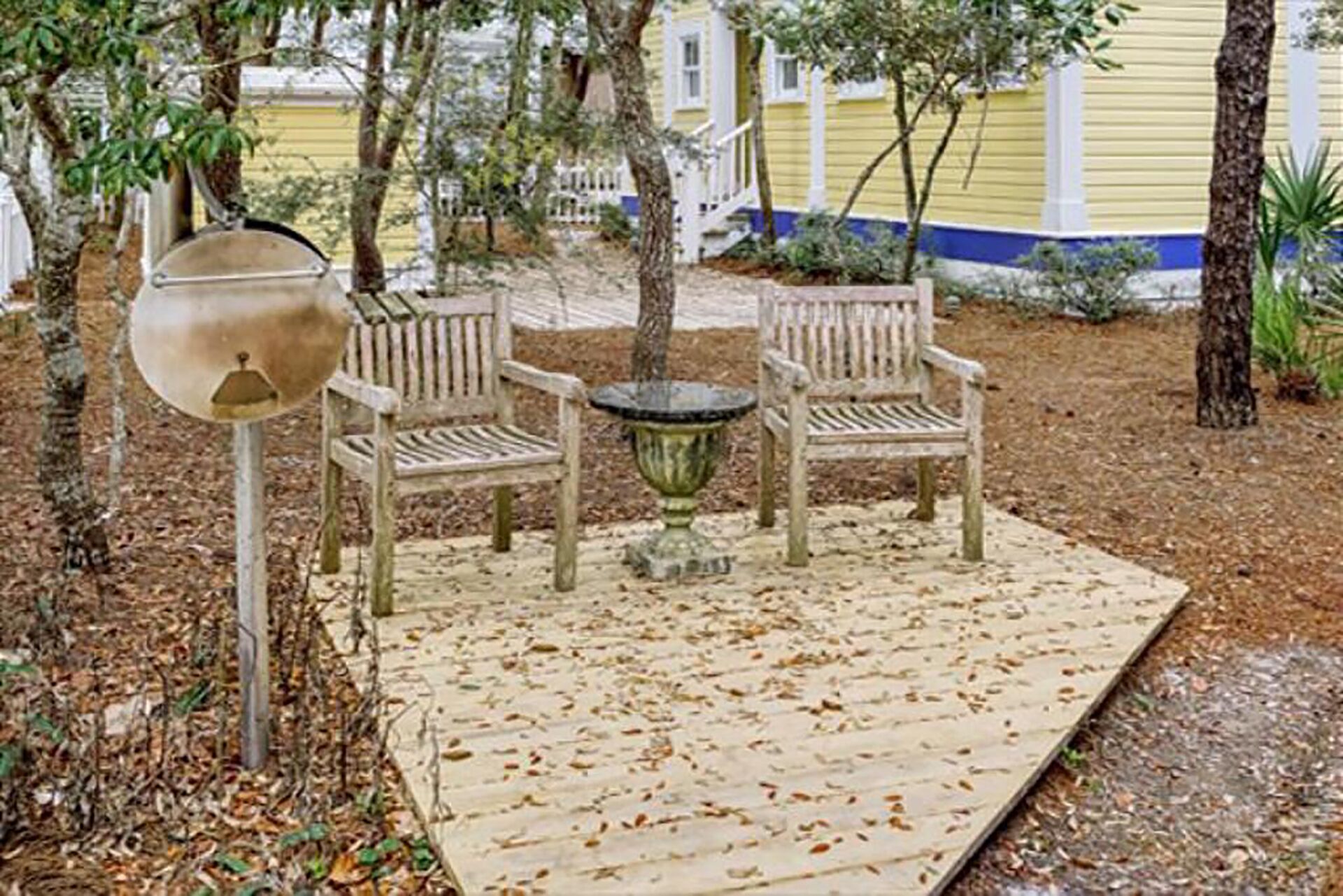 Un espace extérieur aménagé avec une table et deux chaises, entouré d’arbres et doté d’une terrasse en bois.