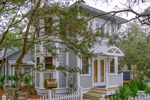 A two-story house with a porch, surrounded by trees.