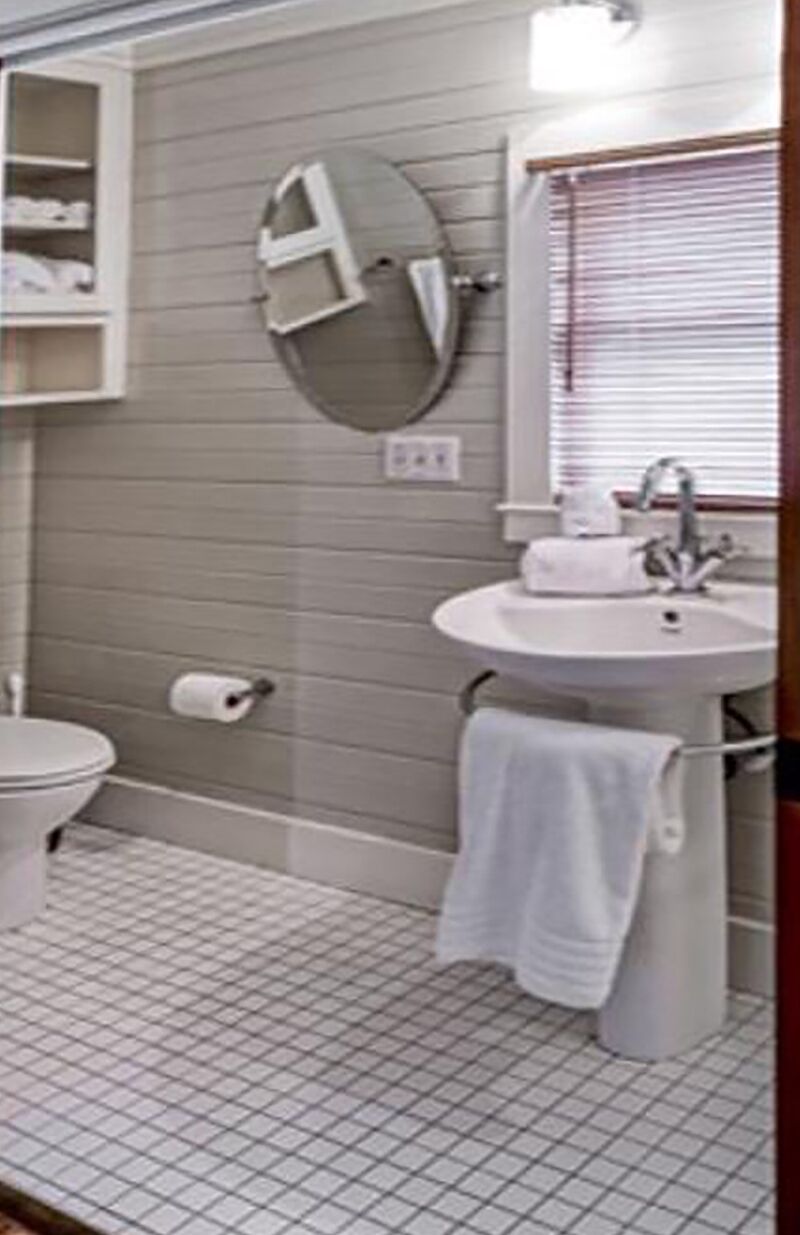A bathroom with a toilet, sink, and mirror.