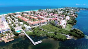 An aerial view of a coastal resort with multiple buildings, a dock, and clear blue waters. - Runaway Bay Resort by BBG (Bradenton Beach)