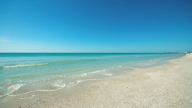 Una playa con agua turquesa cristalina y orilla de piedras.