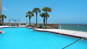 Une piscine à l’eau d’un bleu cristallin, entourée de palmiers et offrant une vue sur l’océan.