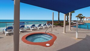 Un espace piscine doté de chaises longues et d’un jacuzzi, avec vue sur l’océan.