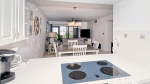Eine moderne Küche mit Einbauherd, weißen Schränken und einem Essbereich mit Tisch und Stühlen.