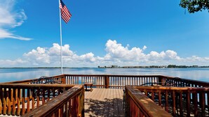 Eine Holzsteg mit Blick auf ruhiges Wasser, eine amerikanische Flagge und einem strahlend blauen Himmel.