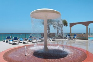 Une fontaine d’eau entourée de chaises longues et un espace aménagé au bord de la piscine offrant une vue dégagée sur l’océan.