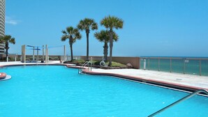 Une piscine à l’eau d’un bleu cristallin, entourée de palmiers et offrant une vue sur l’océan.