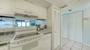 Een keuken met witte kastjes, een fornuis en een raam met uitzicht op het water.