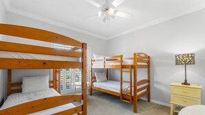 Una habitación con literas, una mesita, una lámpara y un ventilador de techo.