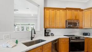 Una cocina con armarios de madera, horno de acero inoxidable y microondas.