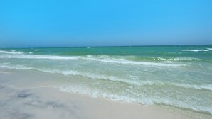A beach with clear blue water and a sandy shore.