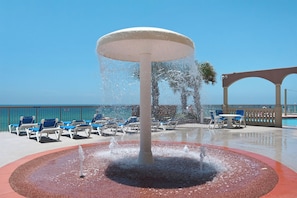 Una fuente de agua rodeada de sillones de descanso y una zona junto a la piscina con vistas despejadas al océano.