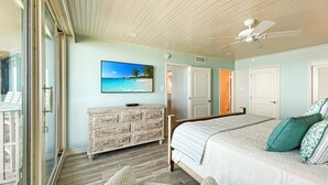 Une chambre à coucher avec un lit, une commode, un téléviseur et un ventilateur de plafond.