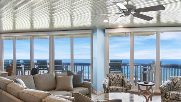 Un balcon spacieux offrant une vue sur l’océan, aménagé avec un canapé, des fauteuils et une petite table.