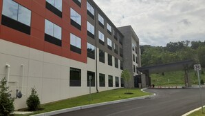 A modern building with a red and white facade, multiple windows, and a parking area with a no parking sign. - Holiday Inn Express & Suites Harrisburg S - Mechanicsburg by IHG (Mechanicsburg)