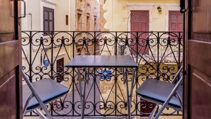A narrow alleyway with a small table and two chairs, enclosed by ornate metal railings. - Alegria (Chania)