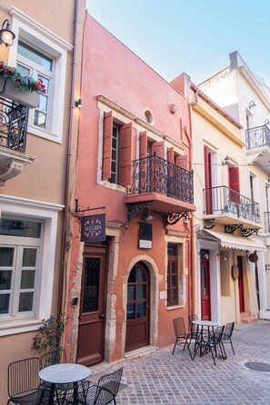 A building with a ground-floor shop named 'ALEGRIA Pension' and a second-floor balcony with a wrought iron railing. - Alegria (Chania)