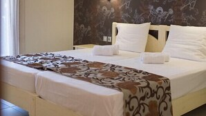 Una habitación de hotel con una cama, una mesita de noche, una lámpara y un papel tapiz estampado.