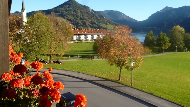 Ein Gebäude mit einem Kirchturm, einem grünen Feld und Bergen im Hintergrund.