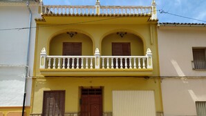 Un edificio de dos pisos con un balcón, una puerta de madera y un portón de garaje.