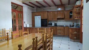 Una cocina con armarios de madera, una mesa de comedor y un refrigerador.