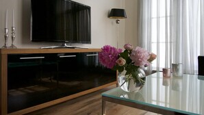 A modern living room with a flat-screen TV, a glass coffee table, and a vase with flowers. - Apartment Faupel (Mülverstedt)