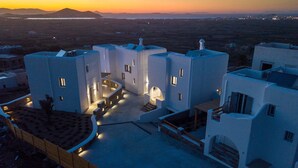 A modern building with a central courtyard, multiple balconies, and a view of the surrounding landscape.