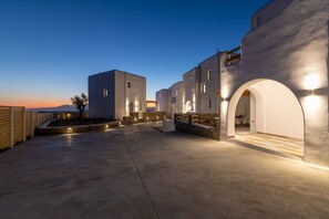 A modern building with a concrete courtyard, stone walls, and illuminated windows. - Naxian Sunset Luxury Villas (Naxos)