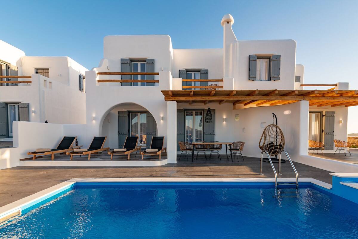 Een moderne villa met zwembad, buitenmeubilair en een overdekt terras.