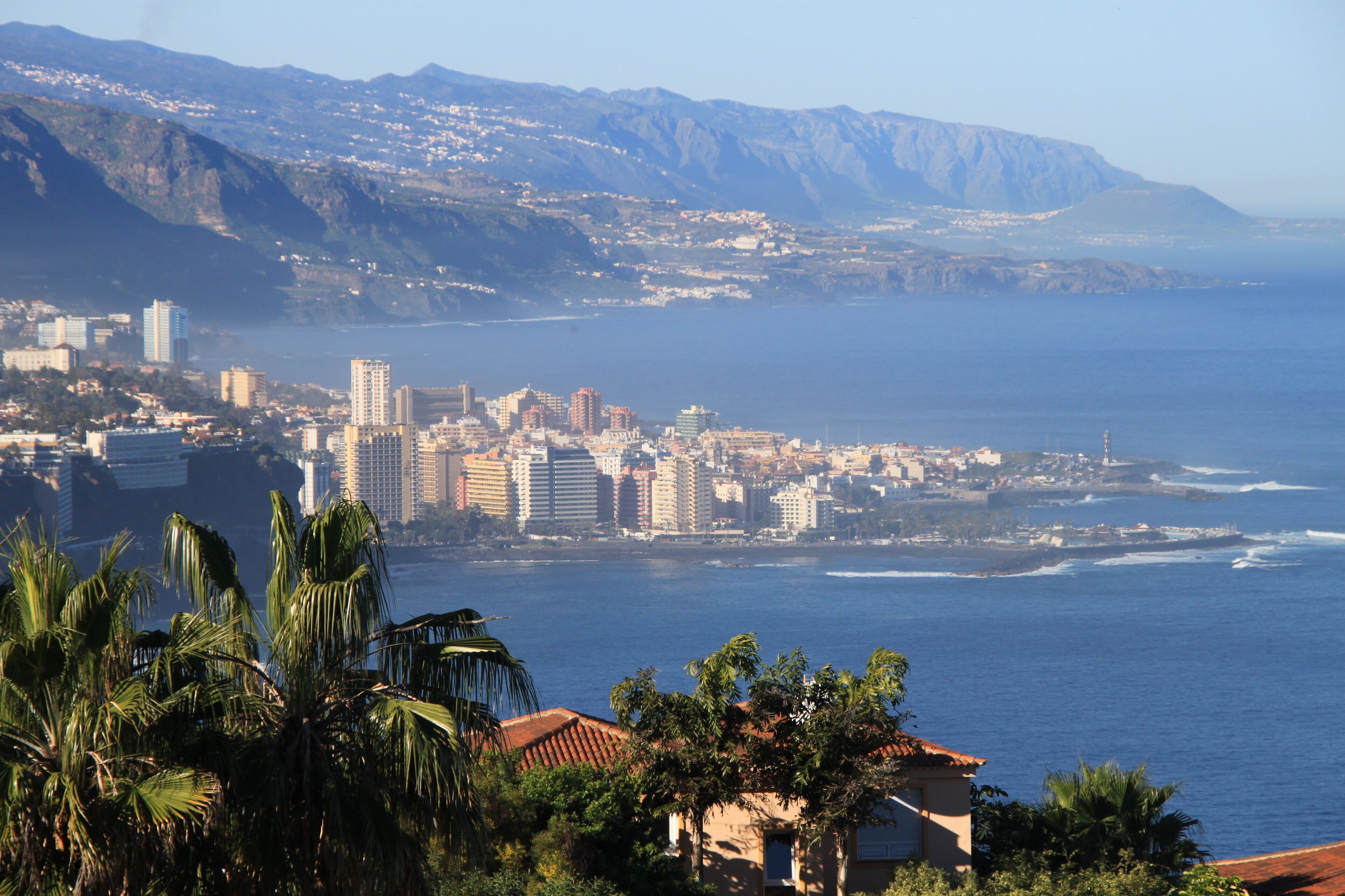 A coastal cityscape with a view of the ocean and mountains in the background.