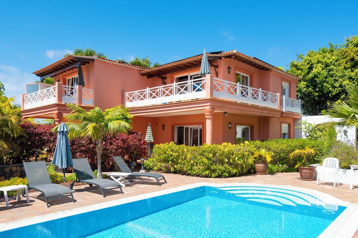 Un bâtiment à deux étages doté d’une piscine, de chaises longues et d’un patio couvert.