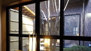 Una habitación con una mesa de este tipo de alfombra de tatami, una linterna japonesa tradicional y vista a una estructura de bambú en el exterior.