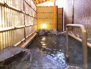 A traditional Japanese onsen with bamboo walls, a stone hot spring, and a wooden walkway. - Kakeyu Onsen Kutsurogi No Yado Kuroiwa Ryokan (Ueda)