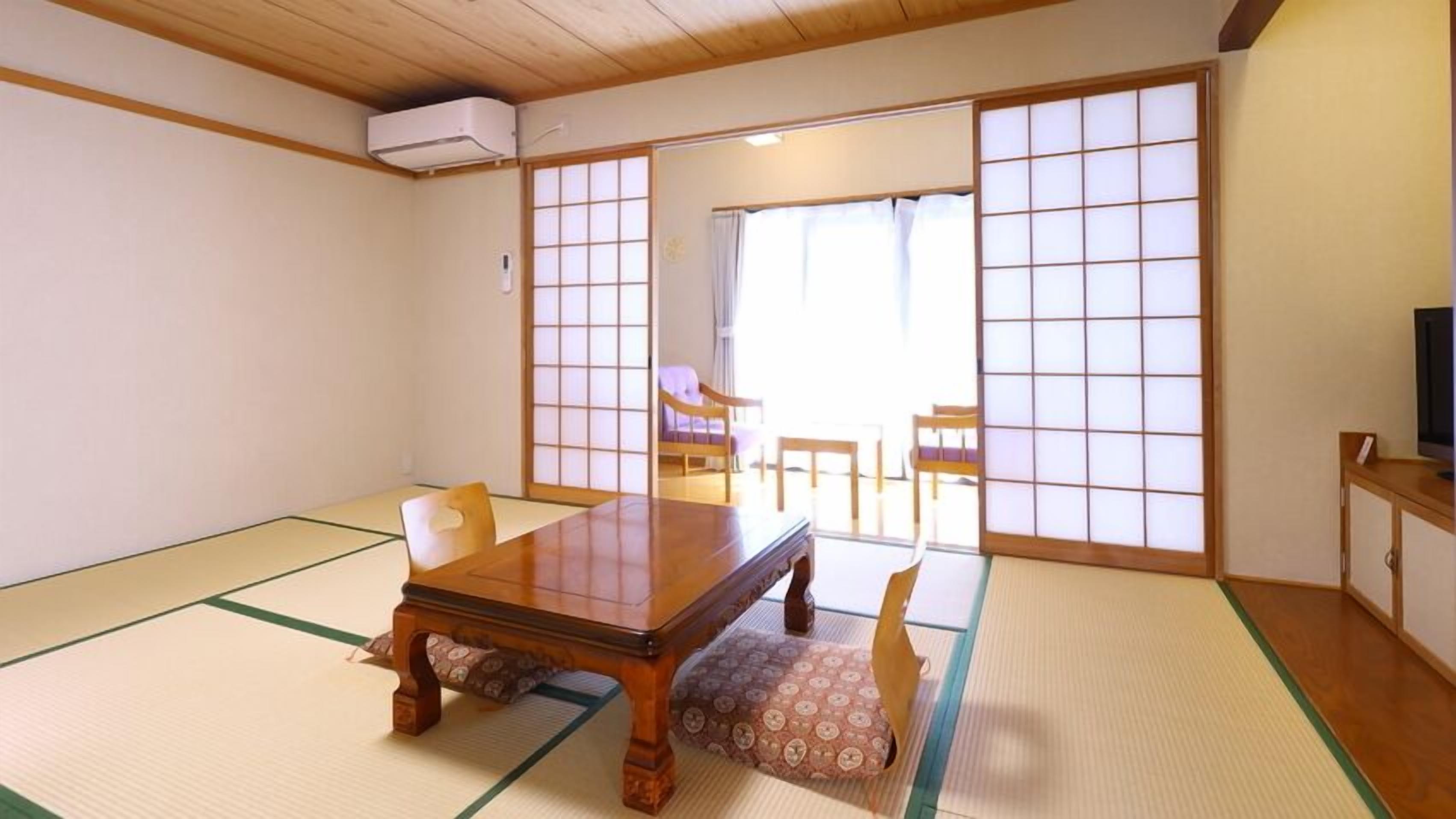 Habitació japonesa tradicional amb sòls de tatami, una taula de fusta baixa i portes corredisses.