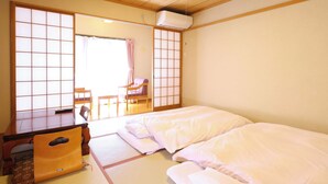 Una habitación japonesa tradicional con suelo de tatami, un futón, un escritorio de madera y una celosía shoji.