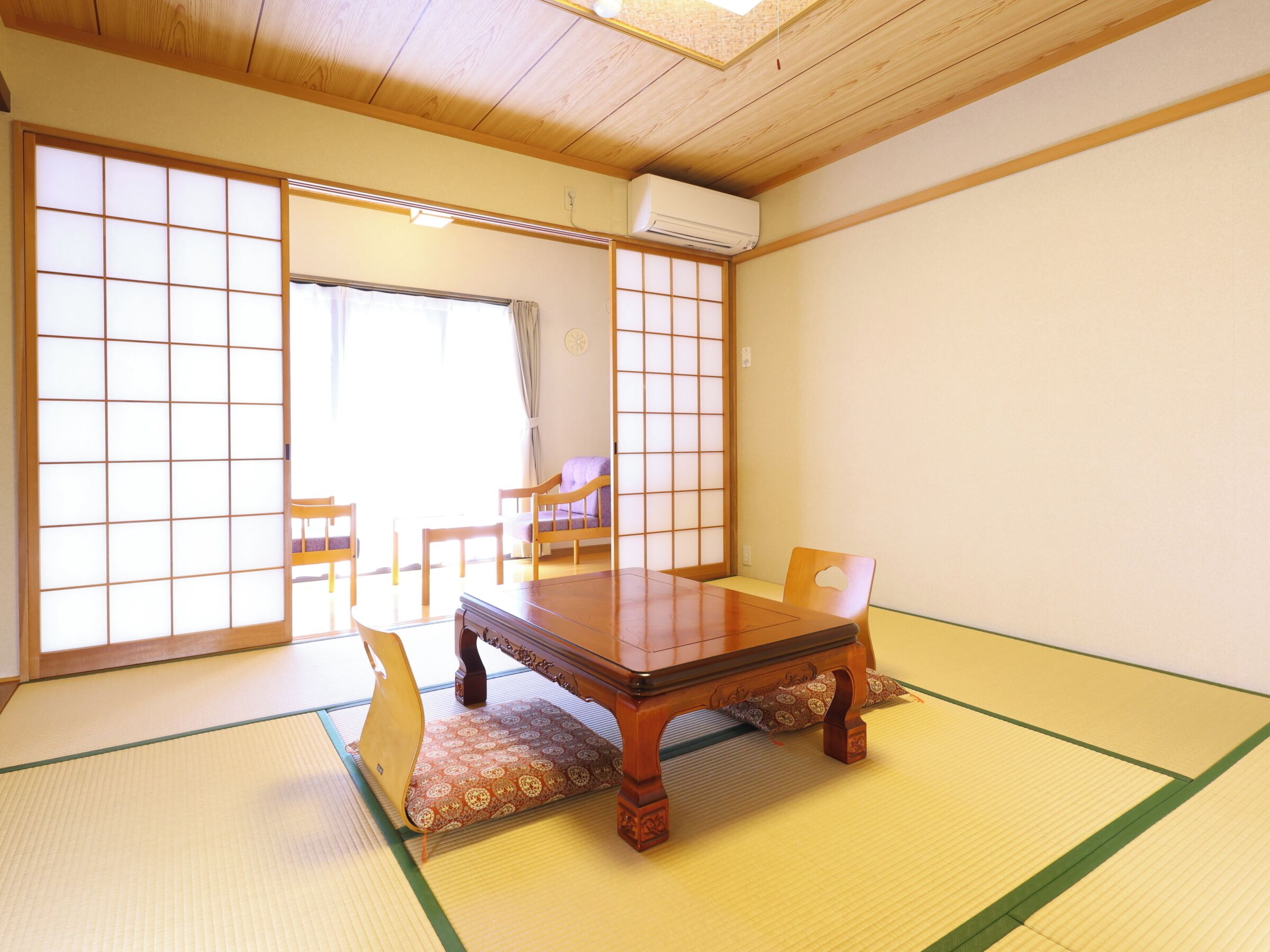 Una habitación japonesa tradicional con suelo de tatami, una mesa de madera y puertas correderas.