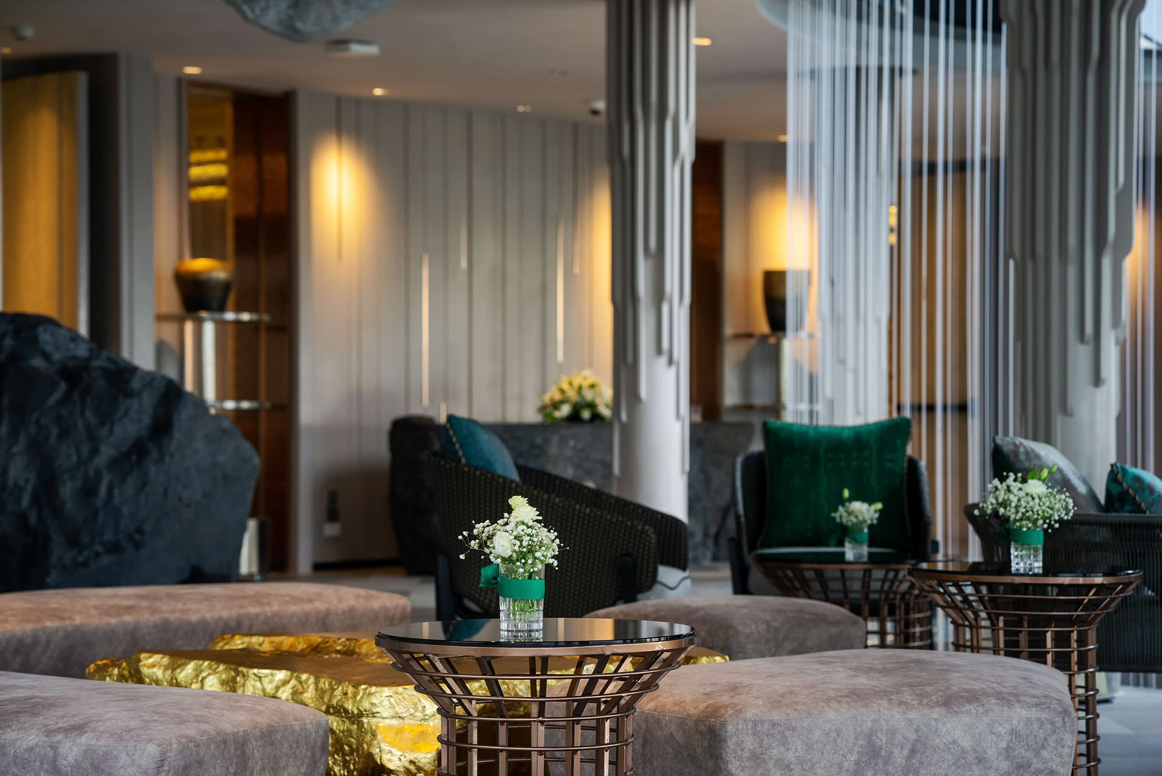 A modern lounge area with round tables, comfortable seating, and decorative vases.