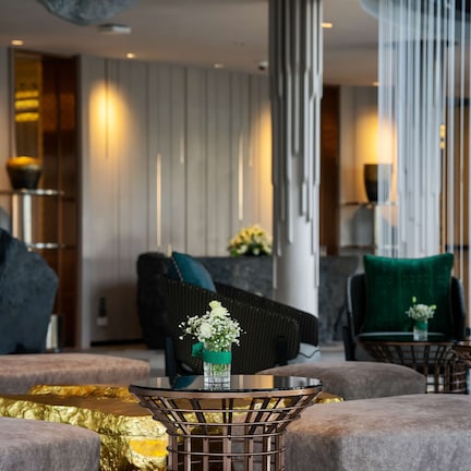 A modern lounge area with round tables, comfortable seating, and decorative vases.