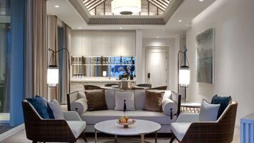 A modern living room with a sofa, two armchairs, a coffee table, and a kitchen area in the background.