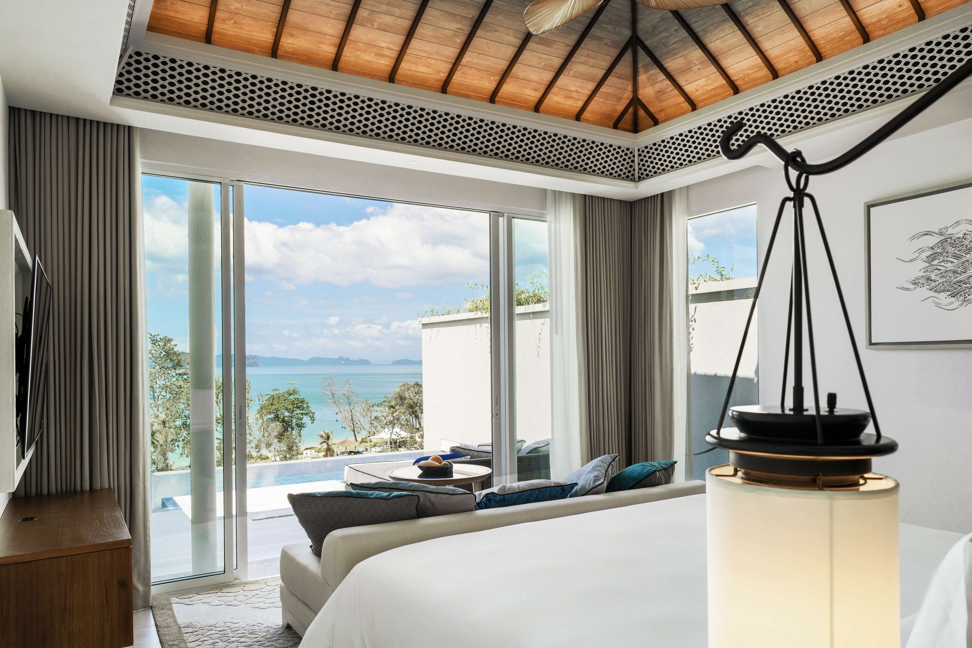 Habitación de hotel moderna con una cama grande, televisión y vista al mar.