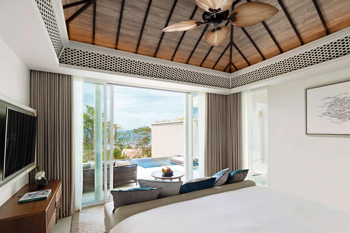 A modern hotel room with a large bed, a TV, a desk, and a balcony with a view.